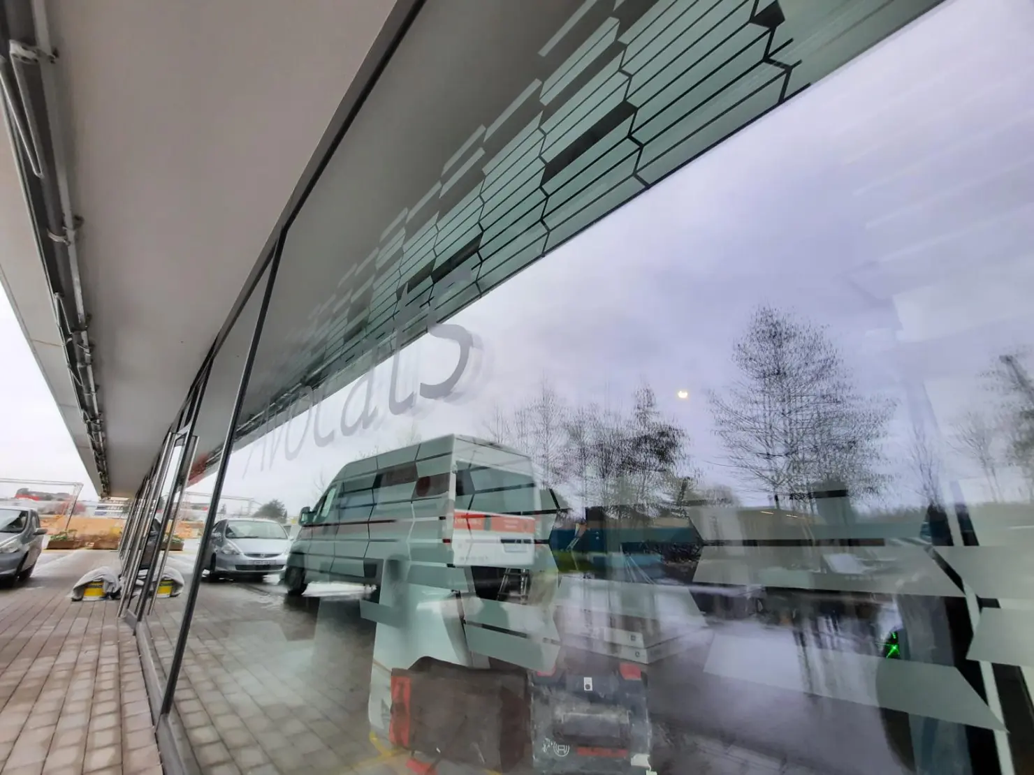 a window of a building with a reflection of vehicles